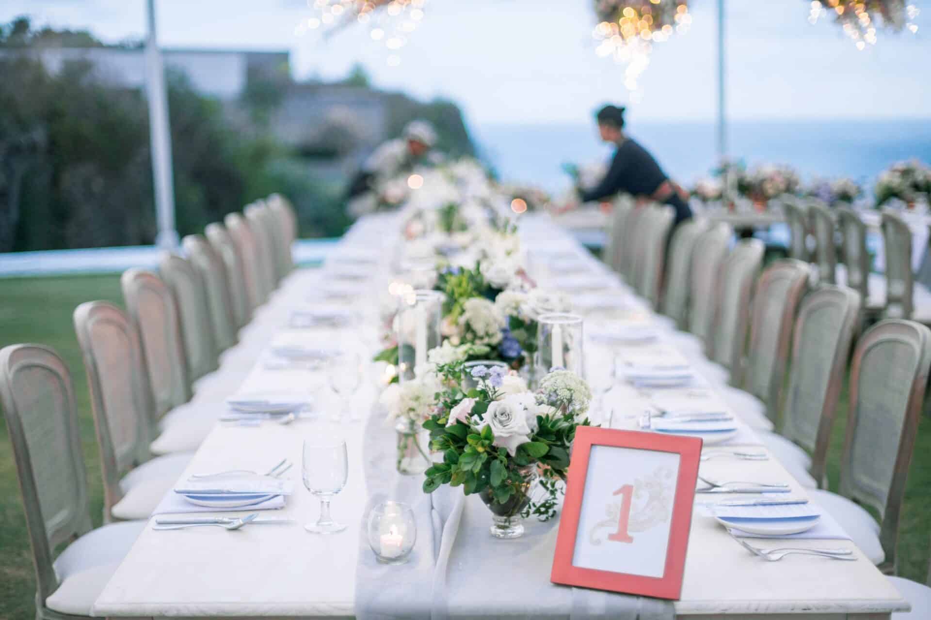 A beautiful outdoor table setting with floral decorations and candles for a wedding reception during daytime