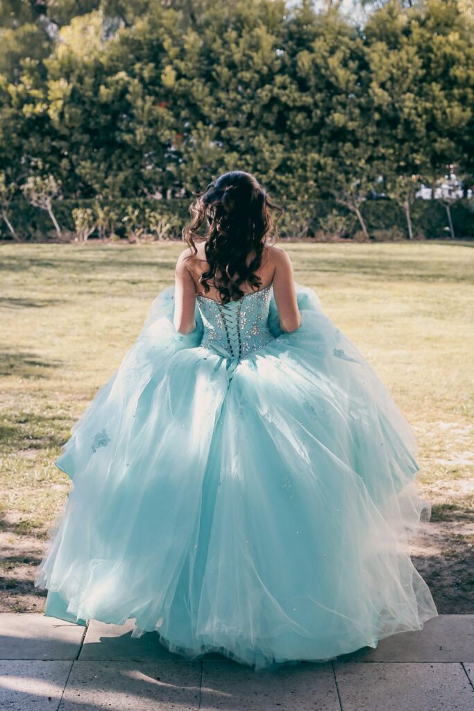 A young lady dressed in her fluffy aqua colored prom dress / quinceanera seen from behind