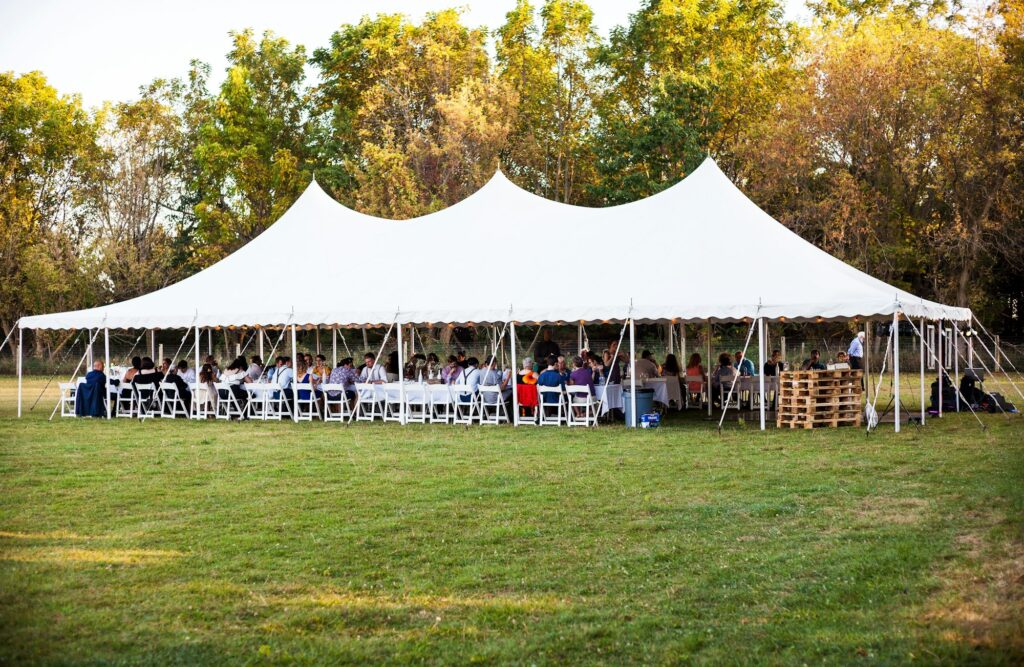 white outdoor tent full of tables and people seated