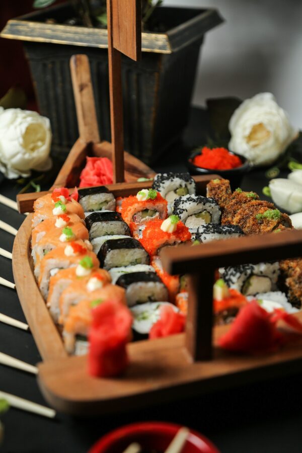 side view mix sushi rolls in a large boat with wasabi and ginger