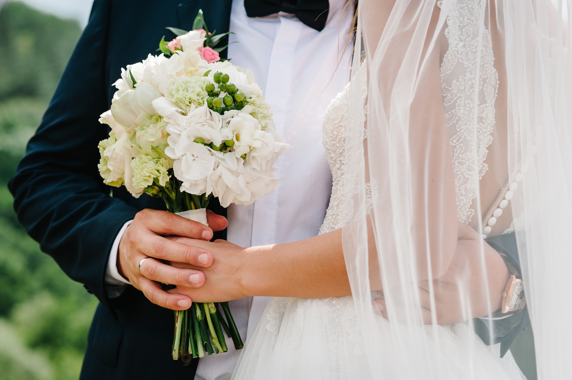 The bride and groom with a wedding bouquet, holding on hands and standing on wedding ceremony