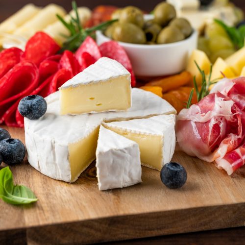 Charcuterie board with a variety of cheeses, salami, chorizzo, prosciutto, nuts, bread, berries
