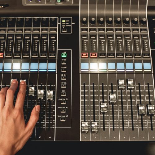 Professional sound control. Close-up view of male hand mixing sounds on digital audio mixing console